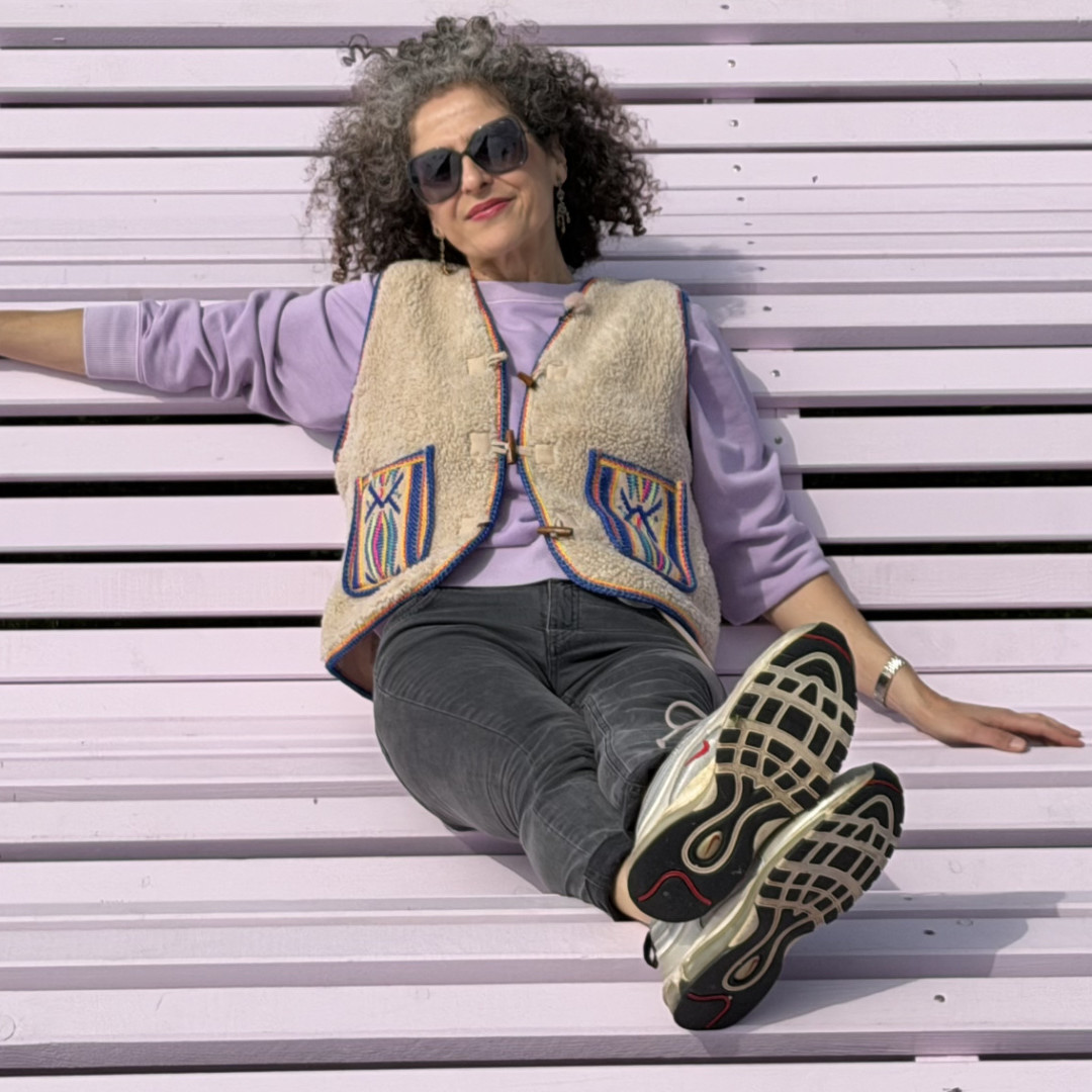 Nora Abu-Oun auf einer pinken Bank liegend mit Sonnenbrille
