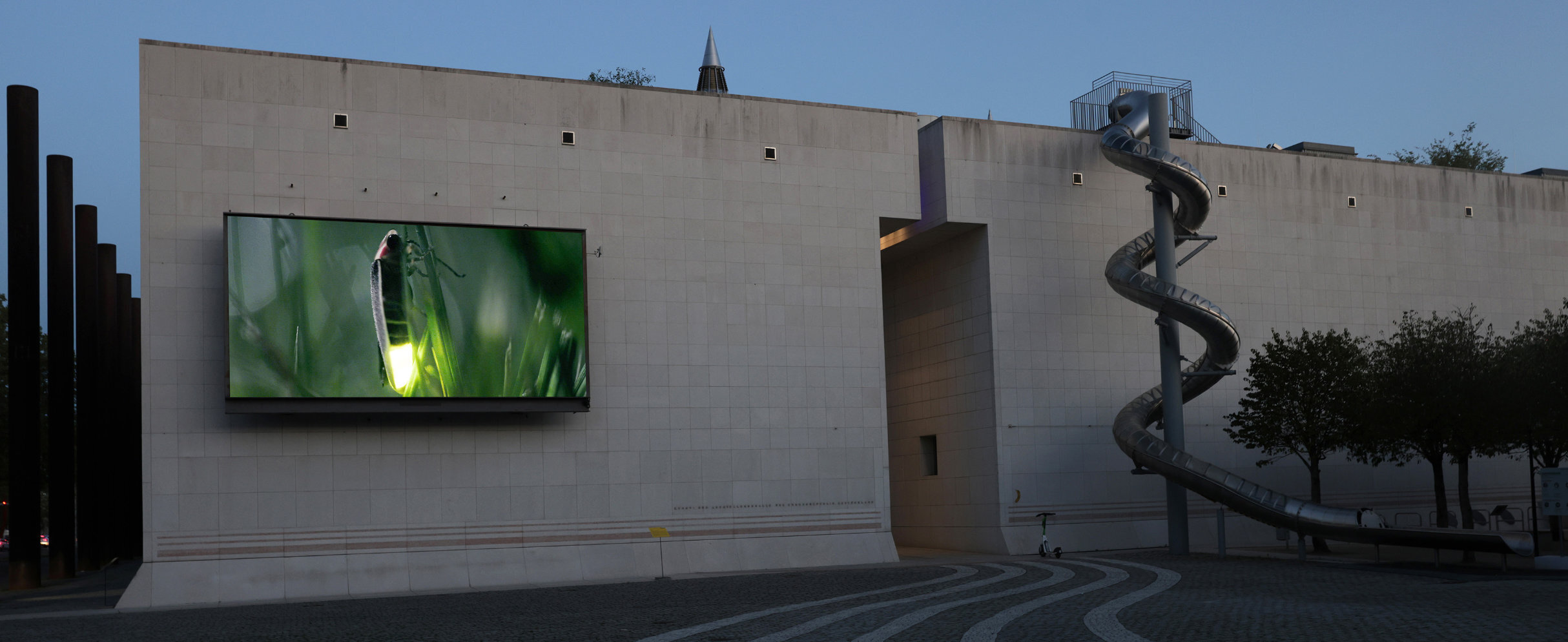Blick auf die Leinwand der Fassade der Bundeskunsthalle. Darauf zu sehen ist ein Glühwürmchen. Es ist das Kunstwerk von Jonas Brinker.