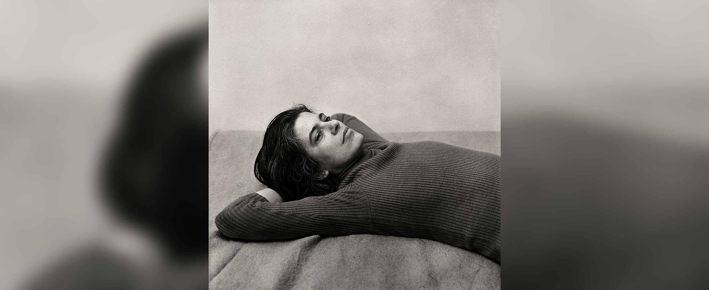 [Translate to English:] Foto von 1975 zeigt Susan Sontag auf dem Rücken, mit Armen unter dem Kopf liegend.